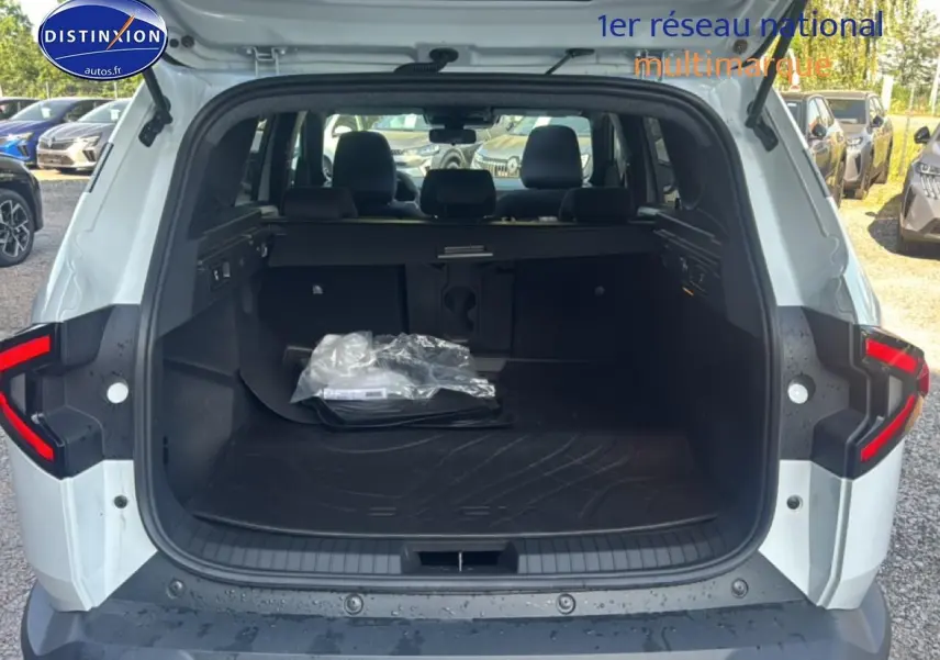 Vue arrière ouverte du coffre blanc du Dacia Bigster 2026 avec tapis de coffre et banquette arrière visible.