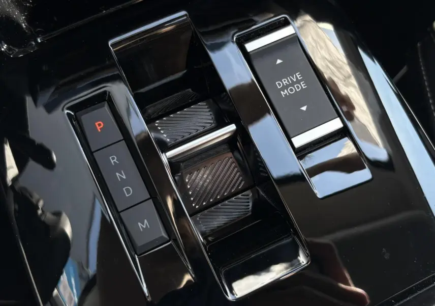Gros plan sur la console centrale noire brillante de la Citroën C4 Hybrid avec commandes de boîte auto et sélection Drive Mode.