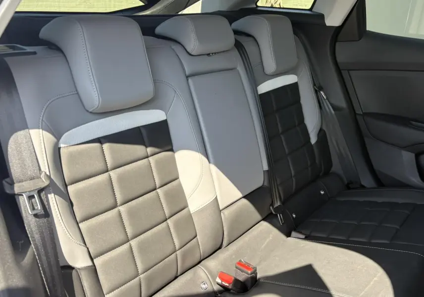 Vue intérieure des sièges arrière en tissu noir et gris clair de la Citroën C4 Hybrid 2025, avec ceintures visibles.
