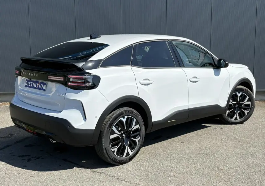 Vue 3/4 arrière droite d'une Citroën C4 Hybrid blanche Okénite avec jantes alliage 18'' diamantées et toit noir brillant.