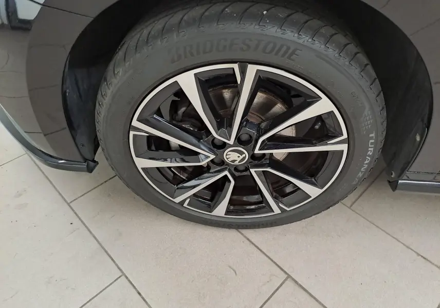 Gros plan sur la roue avant gauche d'une Skoda Fabia 2024 noire avec jante alliage bicolore et pneu Bridgestone.