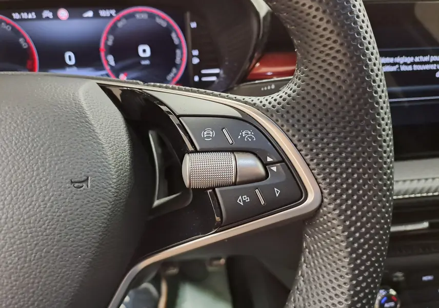 Gros plan sur les commandes à droite du volant perforé d'une Skoda Fabia 2024, tableau de bord numérique en arrière-plan.