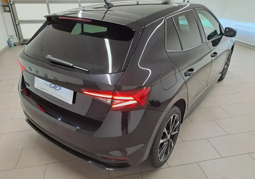 Vue 3/4 arrière droite d'une Skoda Fabia 2024 noire Magic Nacré avec feux arrière LED et jantes alliage.