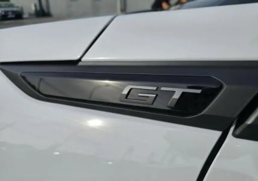 Gros plan sur l’inscription HYBRID noire sur la carrosserie blanche d’un Peugeot 2008 2025.