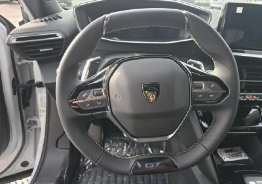 Porte côté gauche ouverte d’un Peugeot 2008 blanc Okenite, intérieur noir avec insert carbone et haut-parleur intégré.