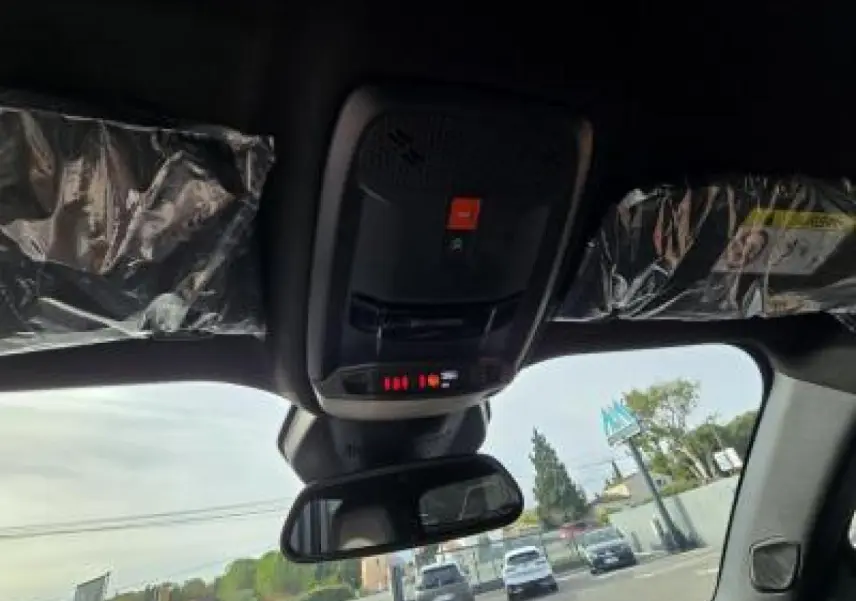 Gros plan sur la palette de changement de vitesse + du volant au cuir noir avec surpiqûres vertes du Peugeot 2008 hybride blanc.