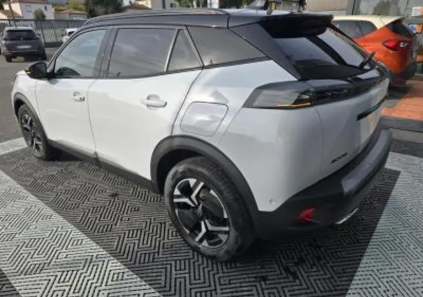 Vue frontale du Peugeot 2008 blanc Okenite avec calandre noire verticale et toit noir brillant.