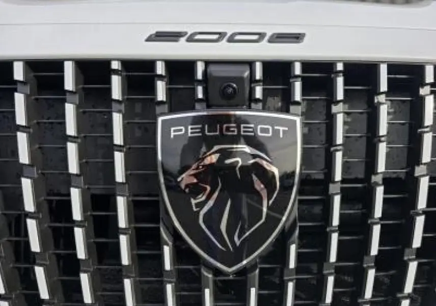 Peugeot 2008 hybride 2025 blanc Okenite toit noir en vue 3/4 arrière côté gauche avec barres de toit noires.