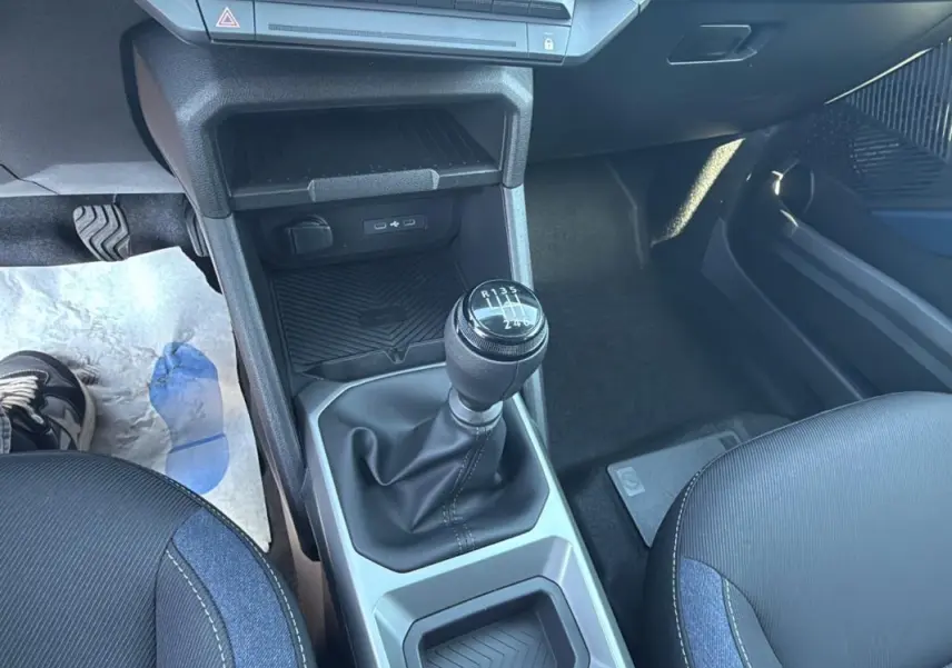 Gros plan sur la console centrale du Dacia Duster 2025, montrant le levier de vitesse manuel et les sièges noirs.