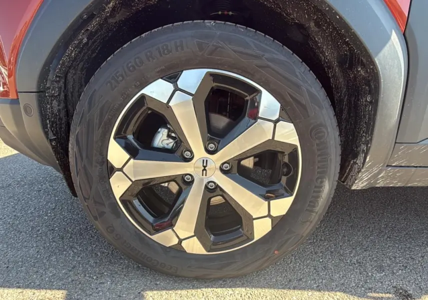 Gros plan sur la jante alliage 18 pouces noire et argent du côté avant droit du Dacia Duster orange 2025.