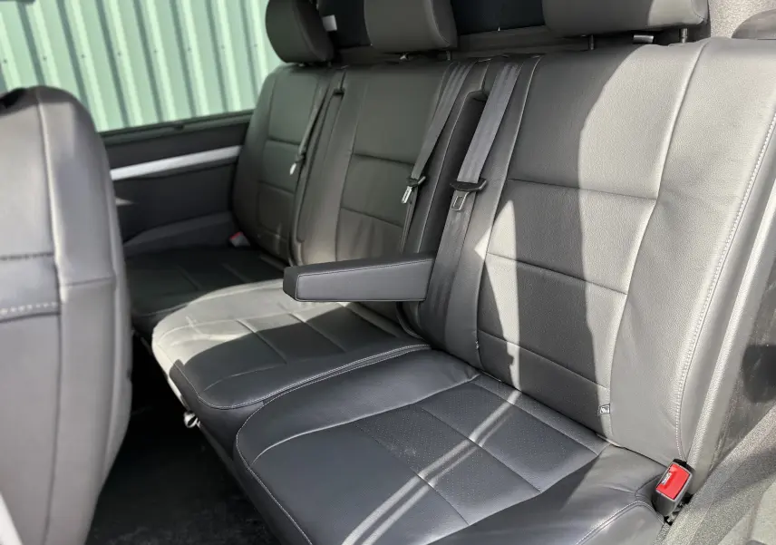 Vue intérieure côté droit des sièges arrière en cuir noir du Citroën Jumpy Cabine Approfondie 2026 avec accoudoir central déployé.
