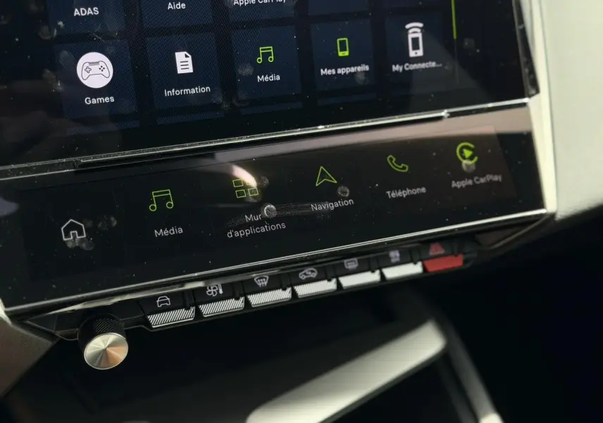 Gros plan sur l’écran tactile central et les commandes de la Peugeot 308 NV Hybrid 145 GT e-DSC6 blanche, intérieur moderne.