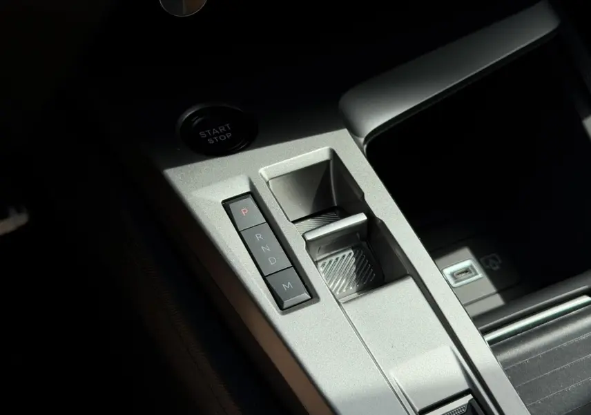 Gros plan sur la console centrale argentée de la Peugeot 308 NV Hybrid 145 GT avec commandes de boîte auto et bouton start/stop.