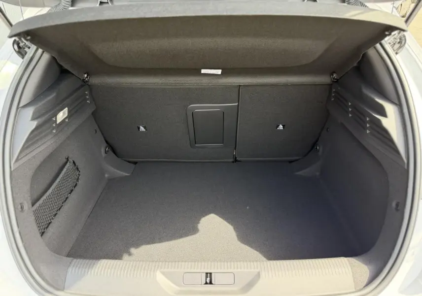 Coffre ouvert vu de l'arrière d'une Peugeot 308 blanc Okenite, avec banquette arrière rabattable et filet de rangement latéral.