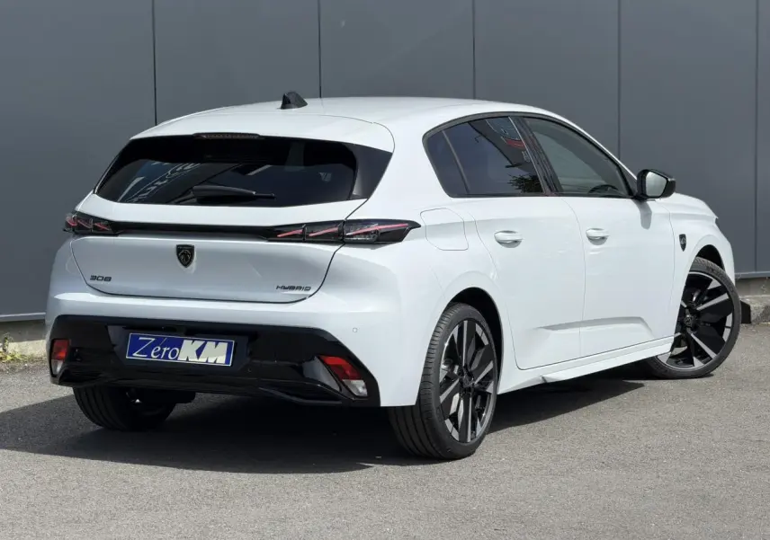 Vue 3/4 arrière droite d'une Peugeot 308 blanche Okenite avec jantes alliage bi-tons et feux arrière LED 3 griffes.