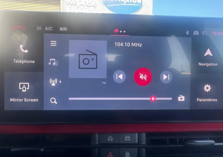 Vue intérieure du tableau de bord du Fiat 600 T-Gen 3 rouge, avec écran tactile multimédia affichant la radio FM.