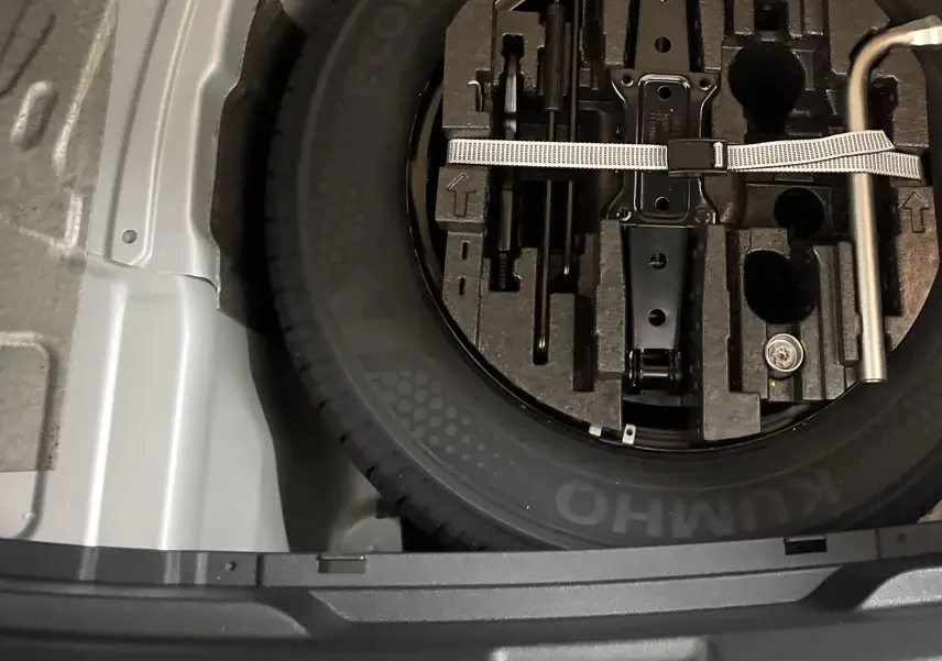 Gros plan sur la roue de secours et les outils de bord dans le coffre d'une Skoda Fabia gris argent 2025.