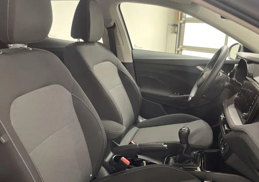 Vue intérieure côté conducteur de la Skoda Fabia 2025 avec sièges tissu gris et levier de vitesses manuel.