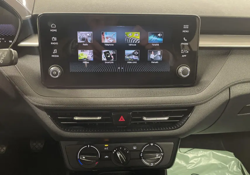 Tableau de bord de la Skoda Fabia 2025 avec écran tactile central et commandes climatisation visibles en intérieur noir.