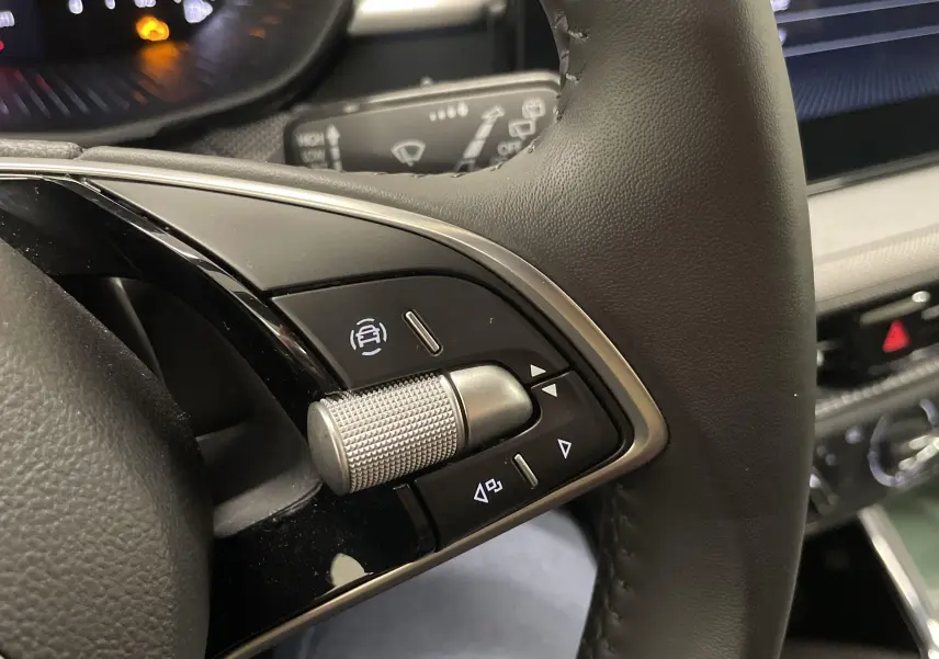 Gros plan sur les commandes gauche du volant en cuir noir de la Skoda Fabia gris argent 2025 avec molette métallique.