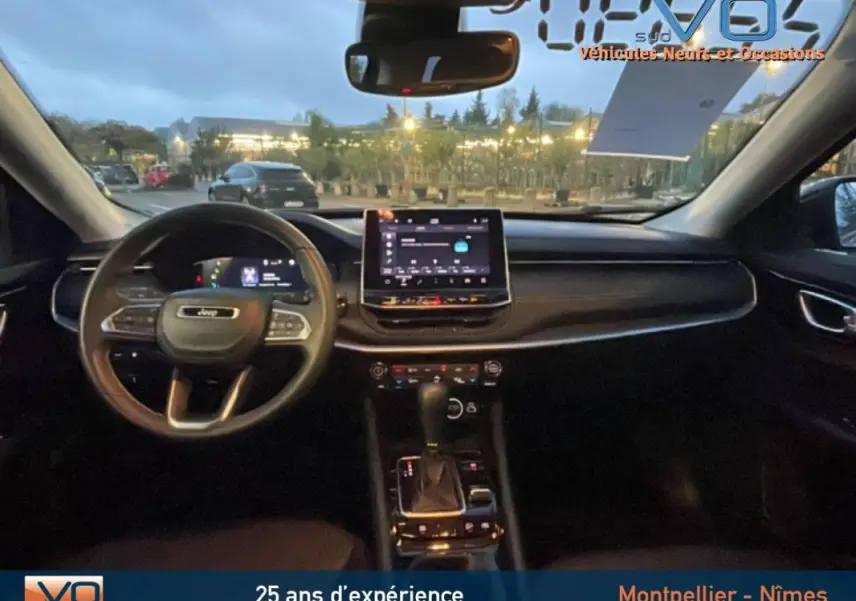 Intérieur du Jeep Compass 2021 en vue frontale, tableau de bord noir avec écran tactile central et volant multifonction.