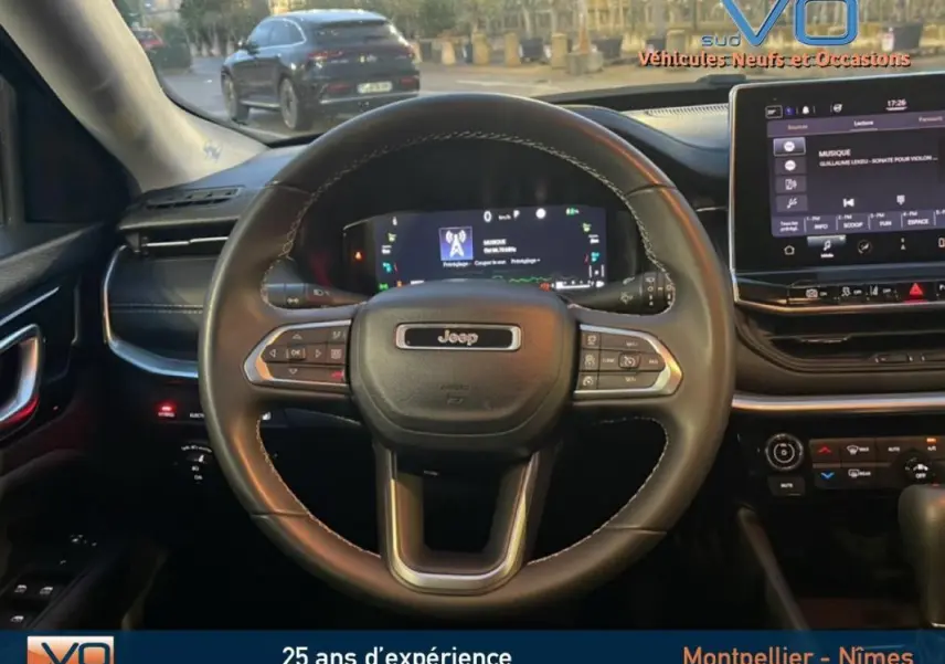 Vue intérieure centrée sur le volant Jeep noir avec tableau de bord numérique et écran tactile du Compass 2021.