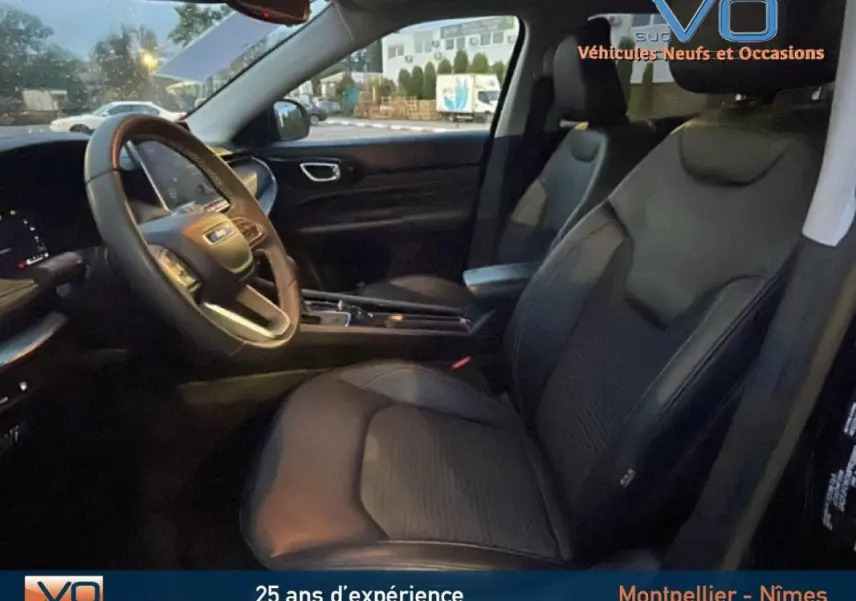 Intérieur du Jeep Compass noir vu côté conducteur, avec sièges en cuir, volant multifonction et accoudoir central visible.