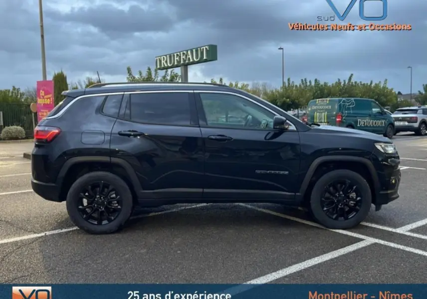 Profil côté gauche d'un Jeep Compass noir 2021 avec jantes alliage noires et barres de toit visibles en extérieur.