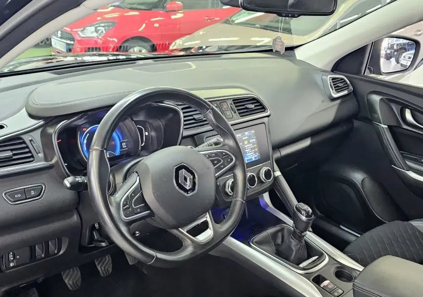 Intérieur du Renault Kadjar noir 2021 vu côté conducteur, volant cuir, tableau de bord avec écran tactile et boîte manuelle.