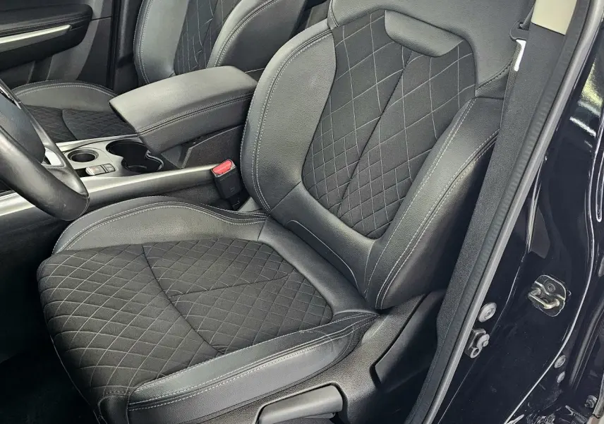 Vue intérieure côté conducteur du Renault Kadjar 2021 noir, montrant le siège en cuir noir matelassé et le volant.