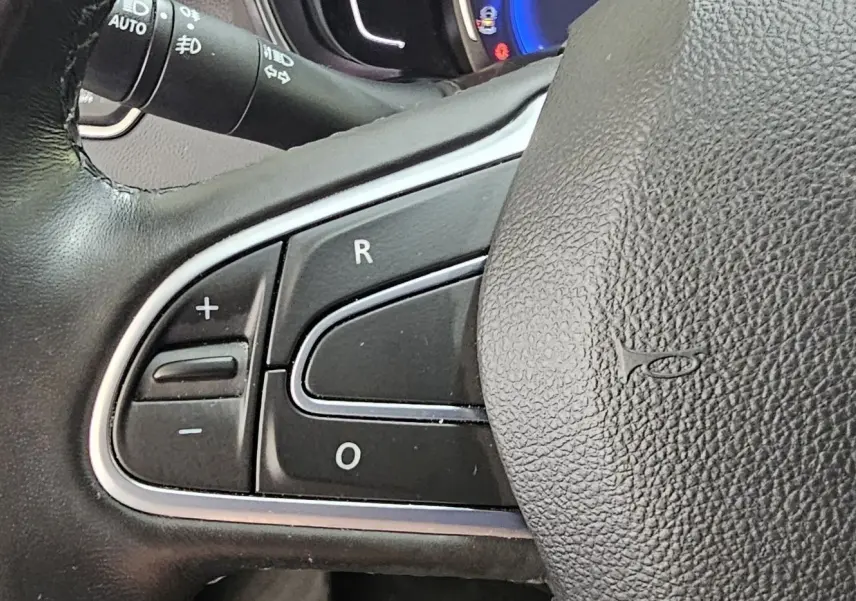 Gros plan sur les commandes de régulateur de vitesse au volant cuir noir du Renault Kadjar 2021 intense.