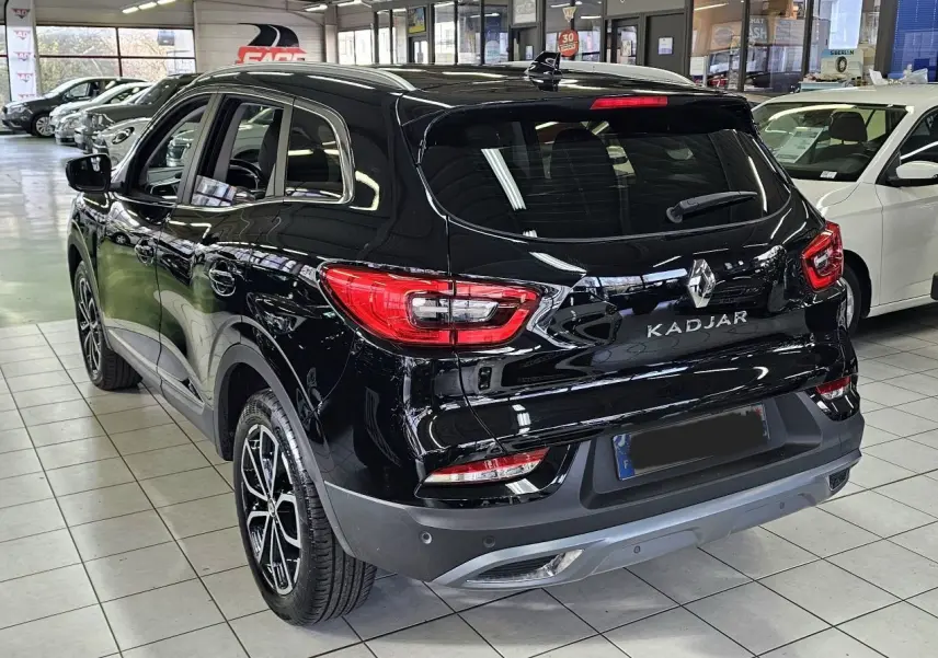 Vue 3/4 arrière du Renault Kadjar noir 2021 en showroom, avec feux arrière et jantes biton visibles.