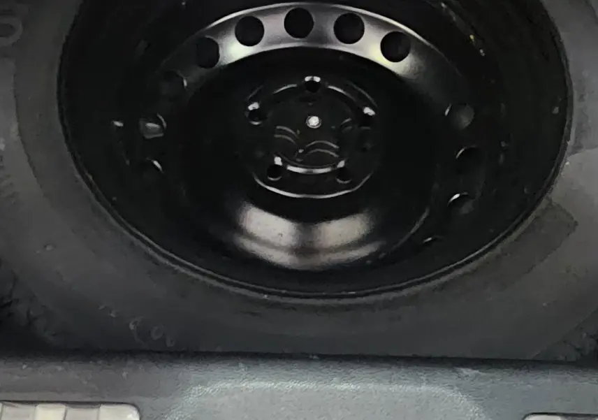 Gros plan sur la roue de secours noire et le cric dans le coffre du Renault Kadjar 2021 intense.