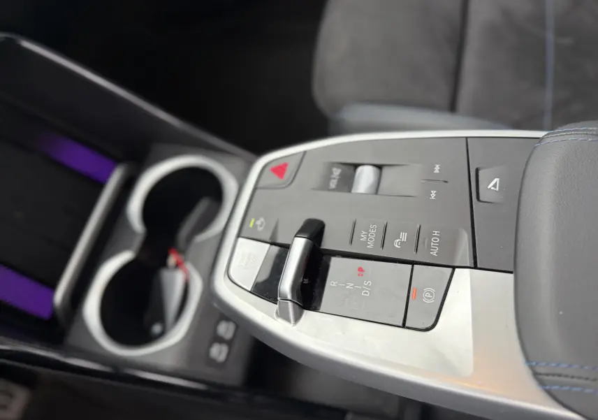 Gros plan sur le volant cuir noir du BMW X1 20D 2025 avec commandes multifonctions et tableau de bord numérique flou.