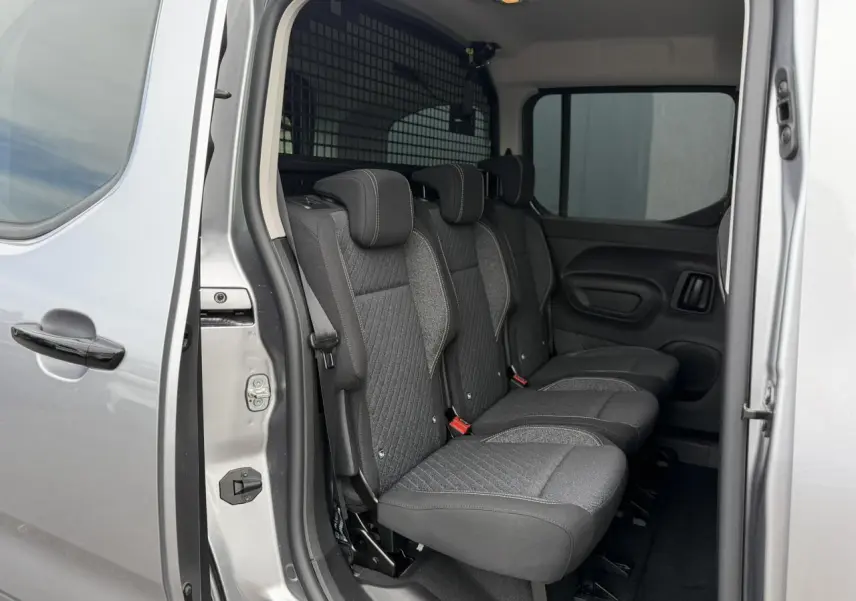 Vue intérieure côté droit des trois sièges individuels arrière du Peugeot Rifter gris acier avec porte coulissante ouverte.