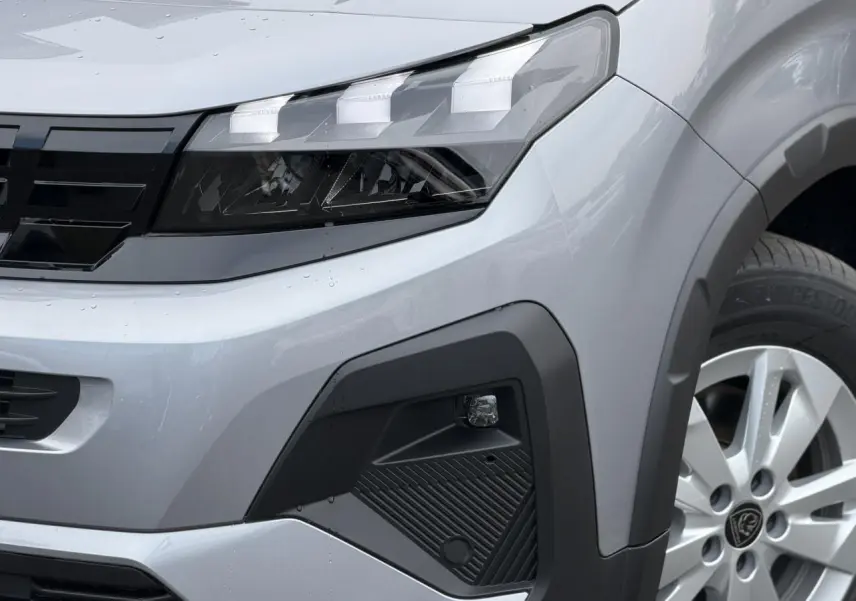 Gros plan sur l'avant droit du Peugeot Rifter gris acier, mettant en valeur le phare LED et la jante alu 16 pouces.