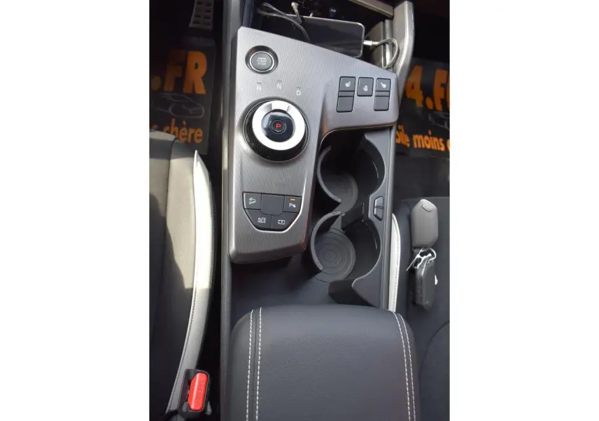 Vue plongeante sur la console centrale noire du Kia Sportage hybride 2026 avec molette de sélection et porte-gobelets.