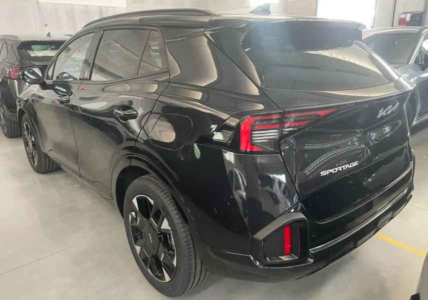 Vue 3/4 arrière droite du KIA SPORTAGE hybride noir 2026 avec feux arrière LED et jantes noires distinctives.