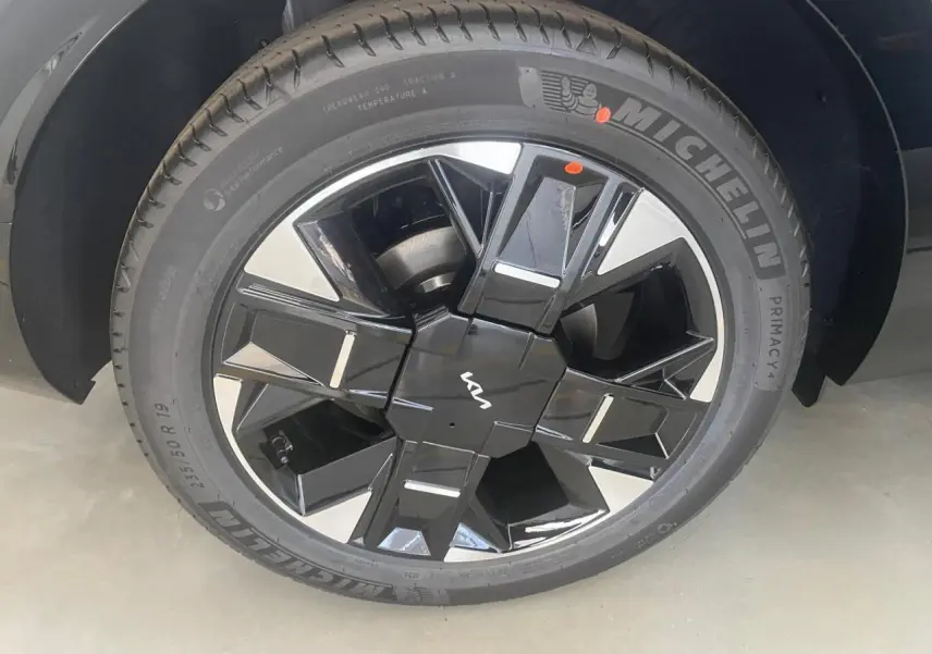 Gros plan sur la jante noire et argentée du Kia Sportage hybride 2026, avec logo Kia au centre et pneu Michelin visible.