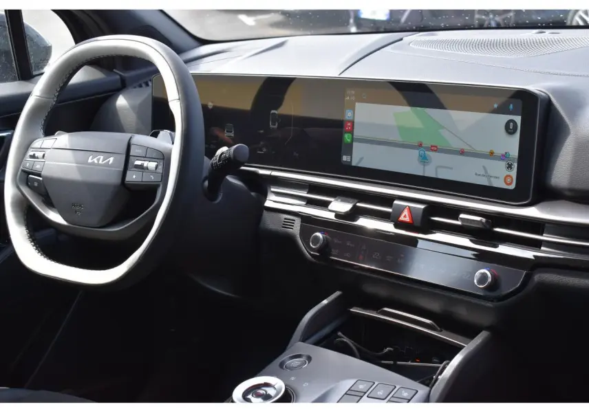Vue intérieure du tableau de bord et volant noir du Kia Sportage hybride 2026 avec écran tactile large et commandes digitales.