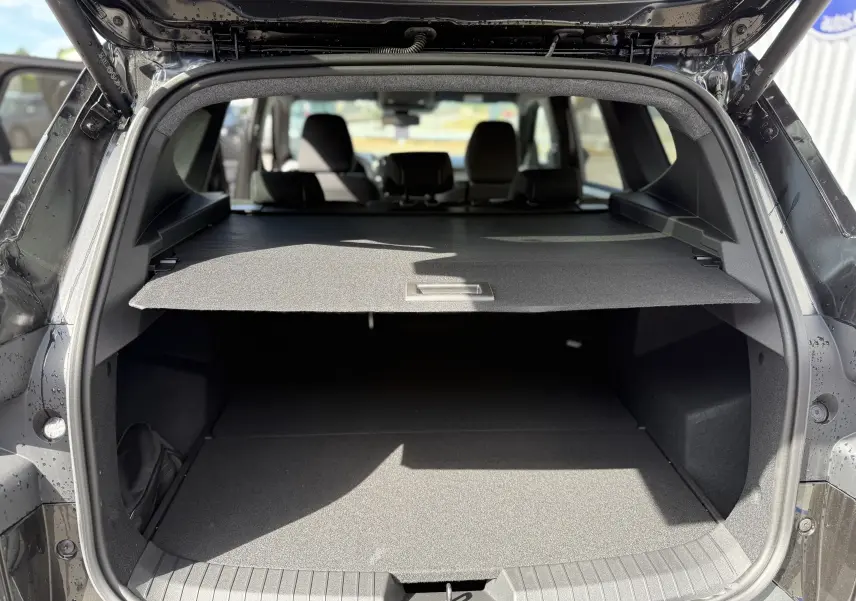 Vue arrière du coffre ouvert du Dacia Bigster noir nacré, montrant la plage arrière et l’espace de chargement.