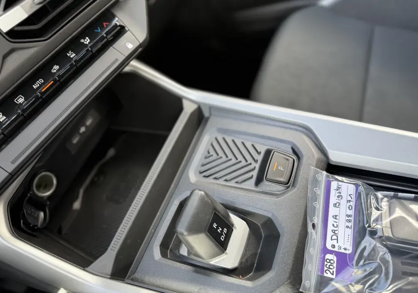 Gros plan sur la console centrale de la Dacia Bigster Hybrid 155 Journey 2026, avec levier de boîte auto et bouton de parking.
