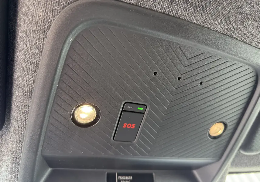 Détail du plafonnier intérieur noir avec bouton SOS rouge et deux lampes allumées dans un Dacia Bigster Hybrid 155 Journey.