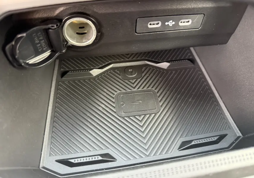 Gros plan intérieur sur le compartiment de recharge sans fil et prises USB du Dacia Bigster Hybrid 155 Journey noir nacré.