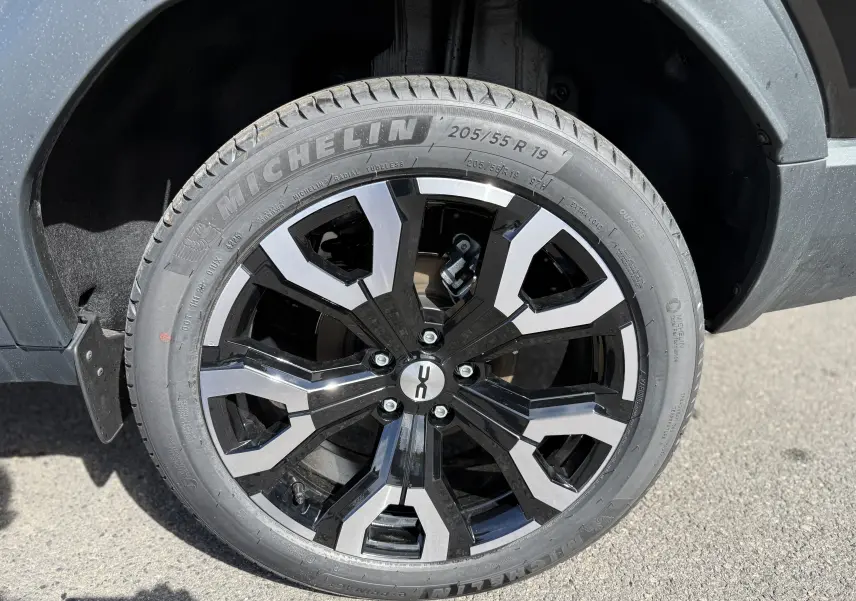 Gros plan sur la roue avant droite du Dacia Bigster noir nacré, jante alliage bicolore 19 pouces au design moderne.