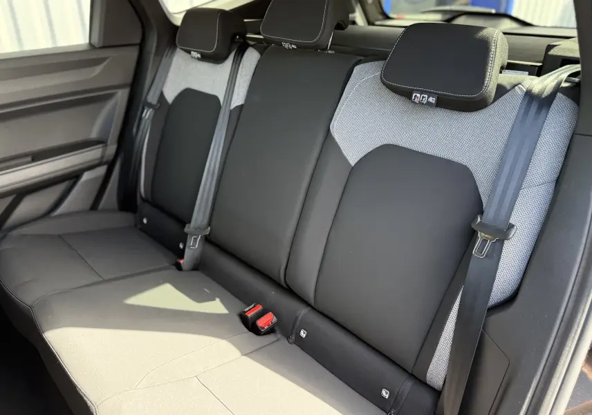 Vue intérieure sur la banquette arrière du Dacia Bigster Hybrid 155 Journey, tissu bicolore noir et gris avec ceintures de sécurité.