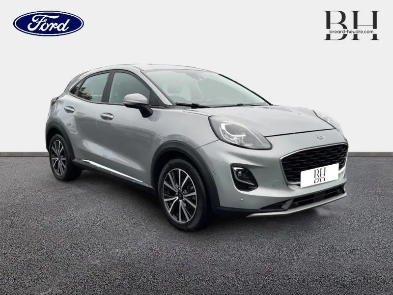 Ford Puma gris Solar métallisé en vue 3/4 avant droit, avec jantes alliage et calandre noire distinctive.