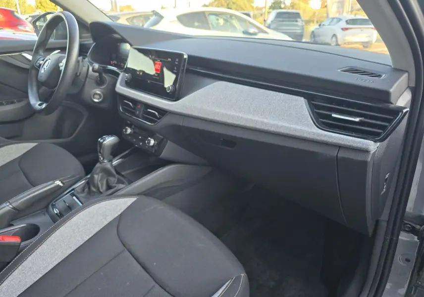 Vue intérieure côté passager de la Skoda Scala gris graphite, montrant tableau de bord et console centrale moderne.