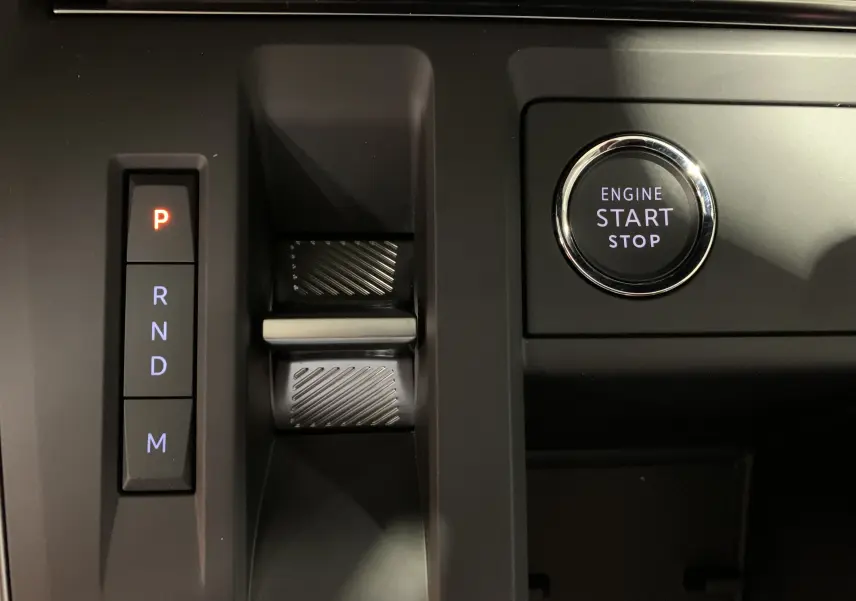 Gros plan sur la console centrale noire du Citroën C5 Aircross hybride 2024 avec bouton Drive Mode et frein à main électronique rouge.