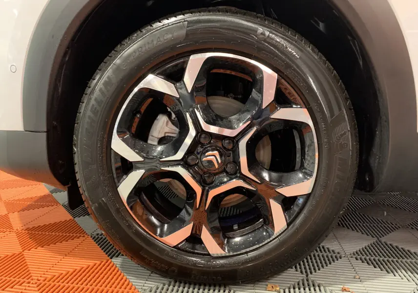 Gros plan sur la jante noire et argentée du côté avant droit du Citroën C5 Aircross Hybride blanc 2024.